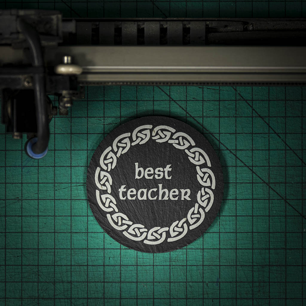 A Welsh slate coaster laser engraved with the words best teacher inside a celtic knot