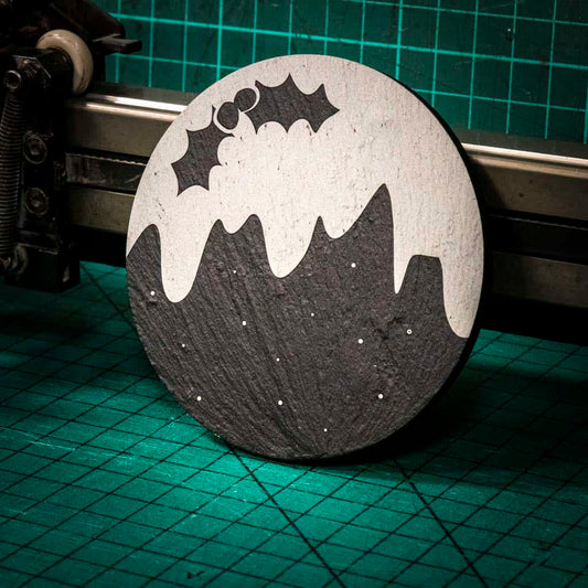 A Christmas themed laser engraved Welsh slate coaster in the design of a christmas pudding