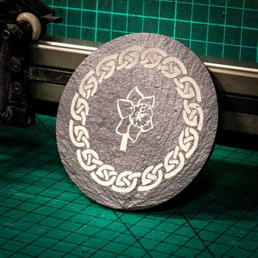 A laser engraved Welsh slate coaster with a welsh daffodil inside a celtic knot boarder
