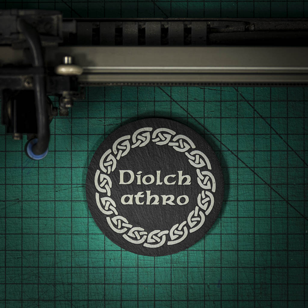A Welsh slate coaster laser engraved with the welsh word for thank you teacher diolch athro, inside a celtic knot