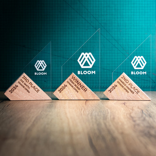 The Genoa Award Range. An Eco-Friendly Wooden and Perspex Award that has a wooden base engraved with a logo and a recyclable clear Perspex triangular shape with a point on the left side of the trophy, which contains the winner and event information.