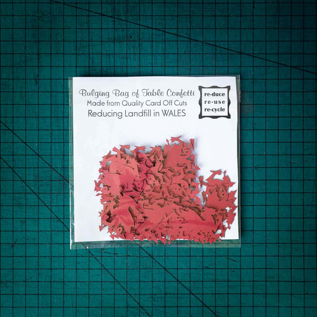 A bag of red dragon confetti laser cut from recycled card