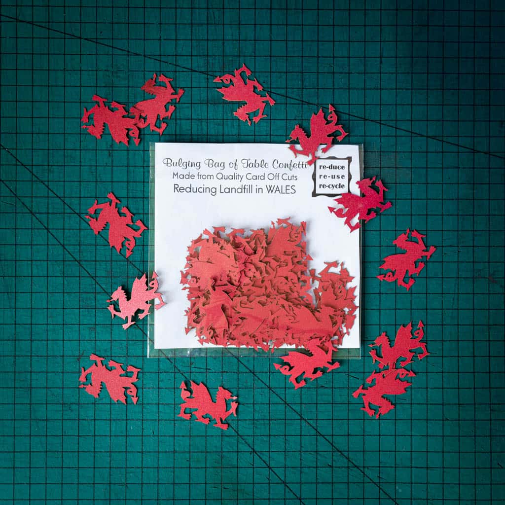 A bag of red dragon confetti laser cut from recycled card