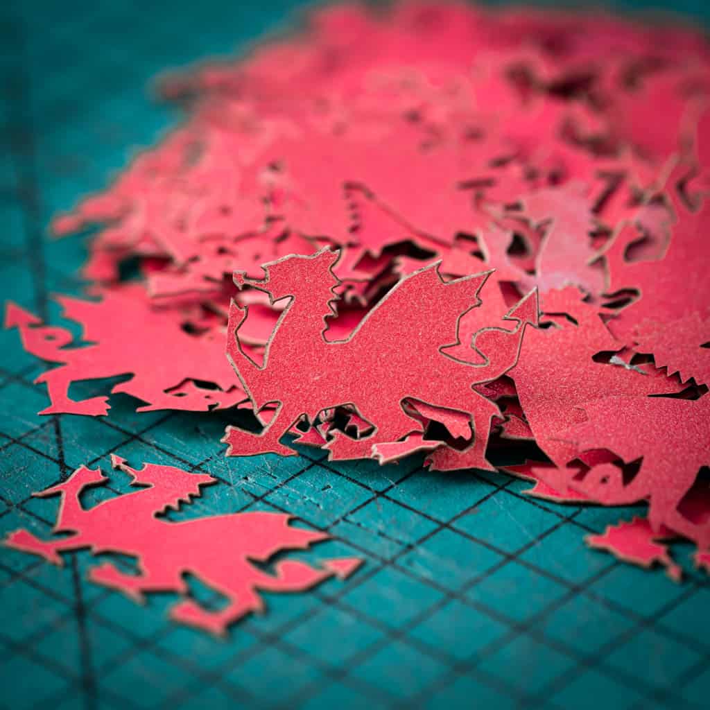 A red dragon confetti laser cut from recycled card