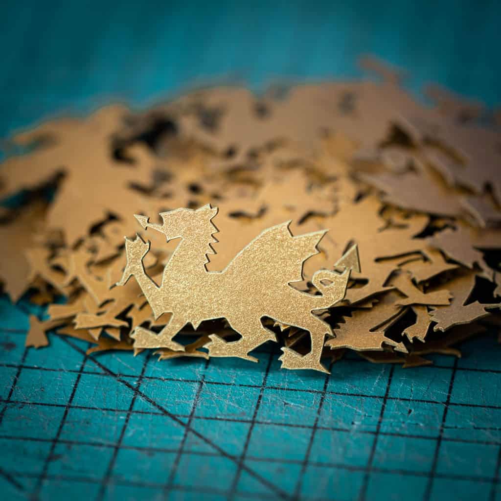 A golden dragon confetti laser cut from recycled card