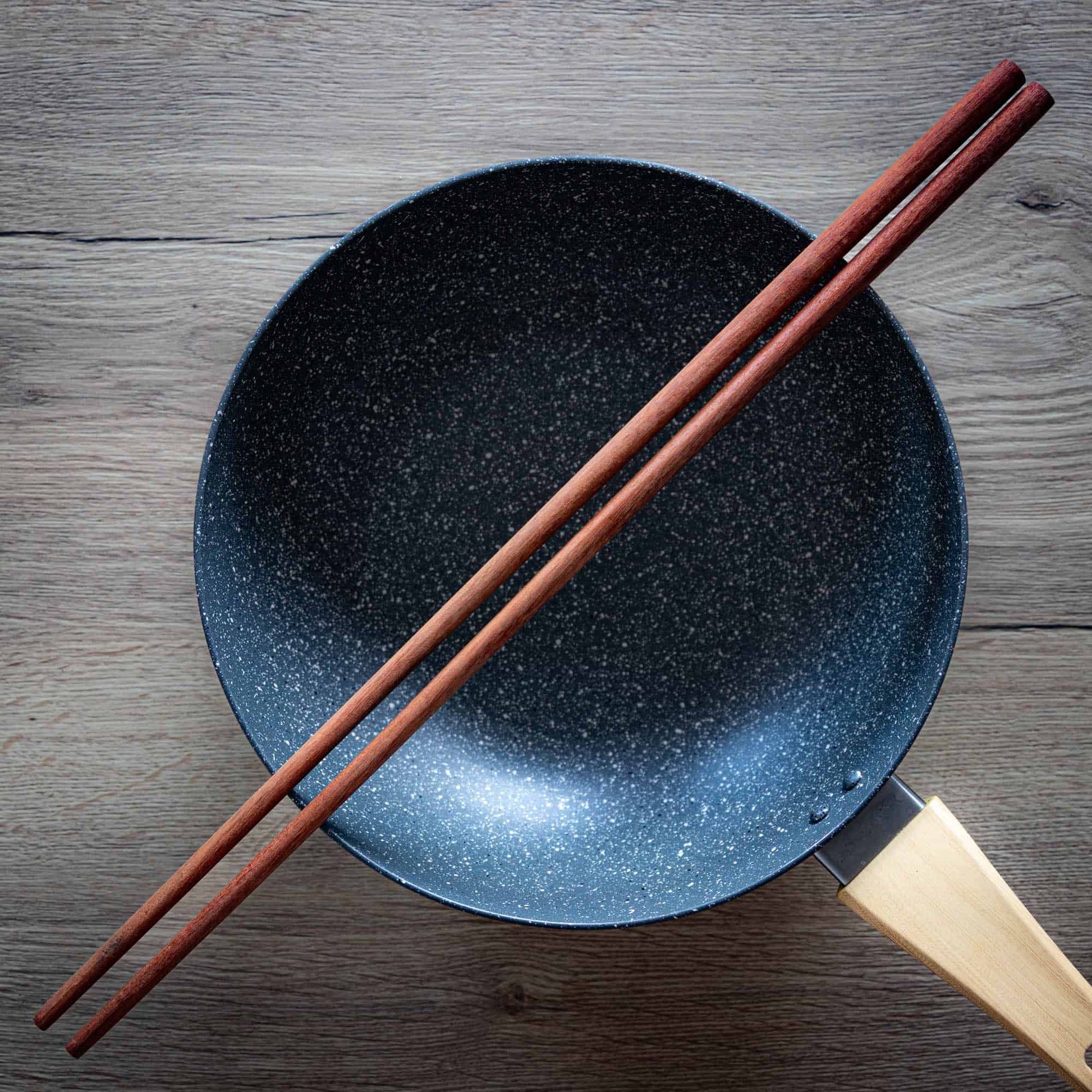 Long wooden cooking chopsticks on a wok