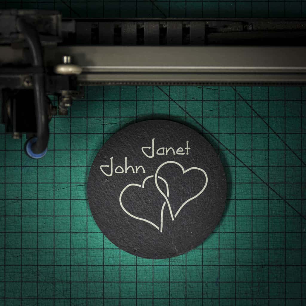 A personalised Welsh slate coaster laser engraved with two intertwined hearts and two names
