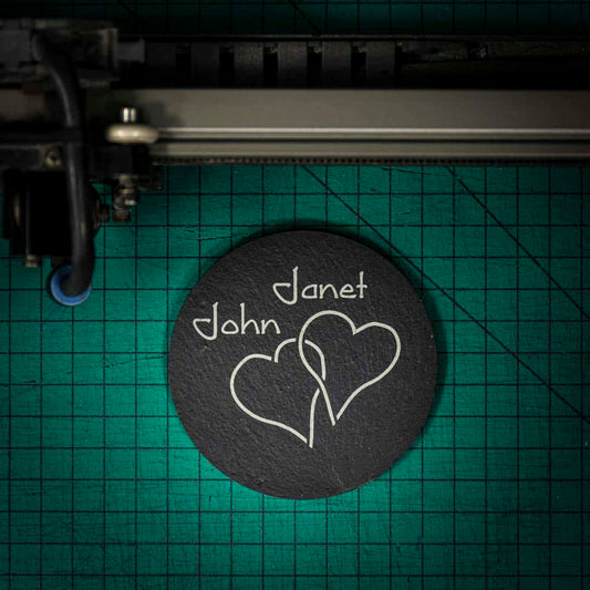 A personalised Welsh slate coaster laser engraved with two intertwined hearts and two names
