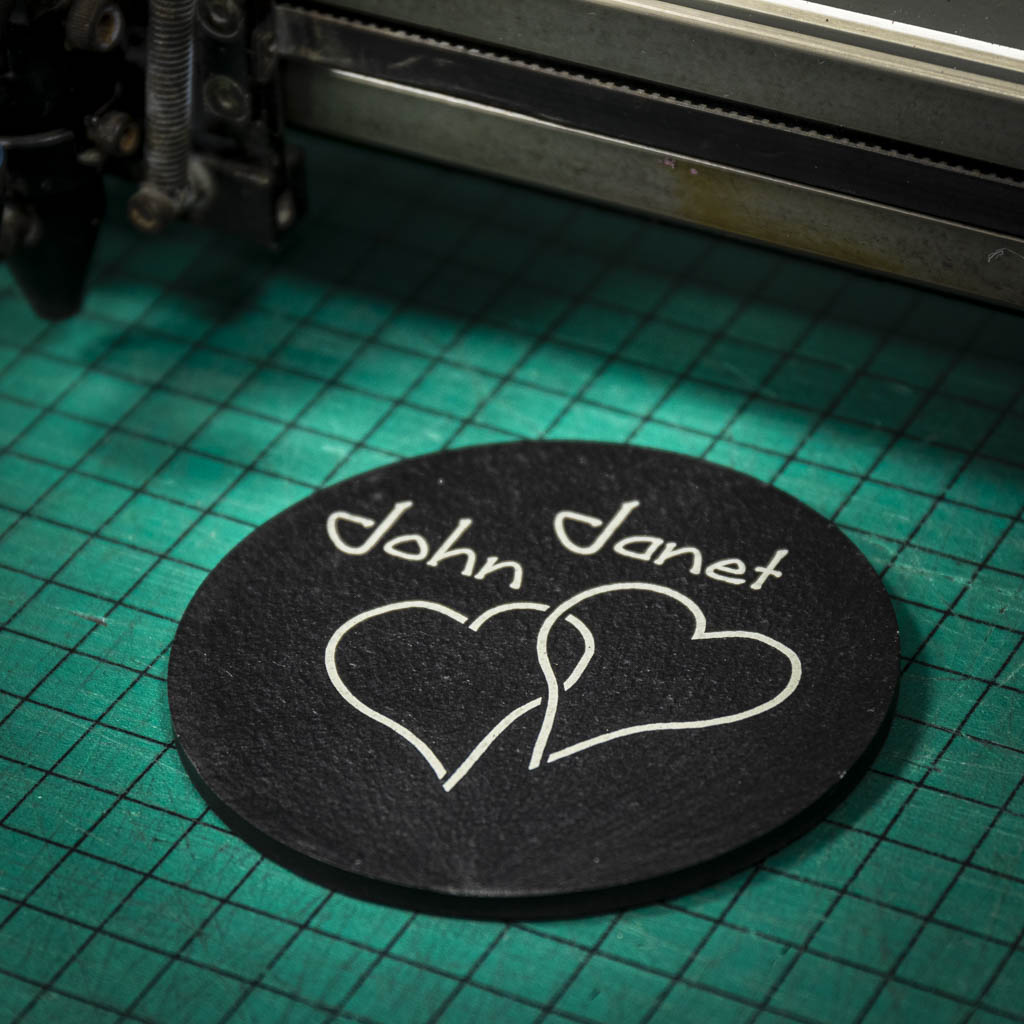 A personalised Welsh slate coaster laser engraved with two intertwined hearts and two names