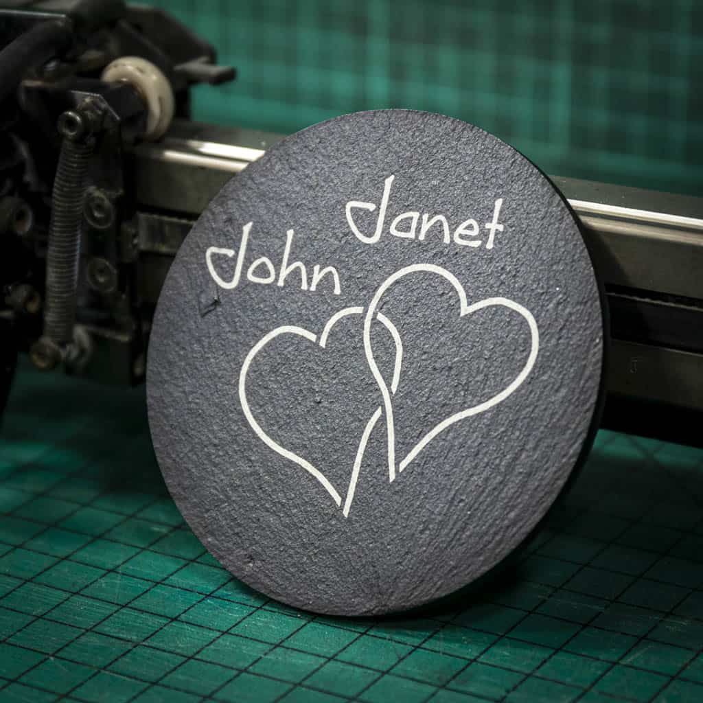 A personalised Welsh slate coaster laser engraved with two intertwined hearts and two names