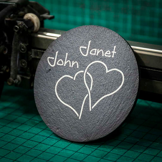 A personalised Welsh slate coaster laser engraved with two intertwined hearts and two names