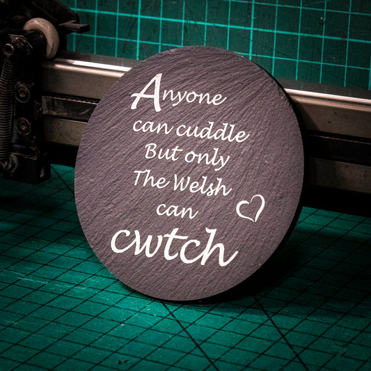A laser engraved Welsh slate coaster with the words anyone can cuddle but only the welsh can cwtch