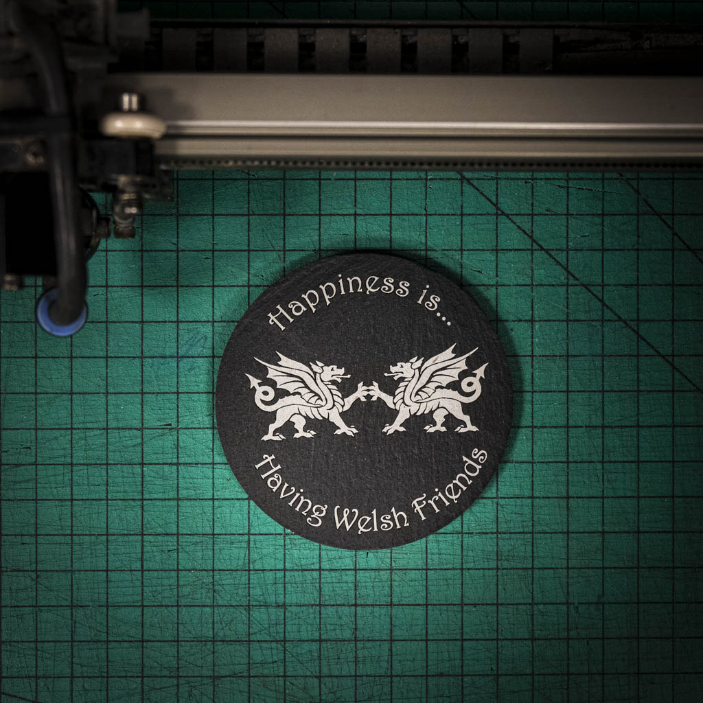 A laser engraved Welsh slate coaster with two welsh dragons and the words happiness is having welsh friends