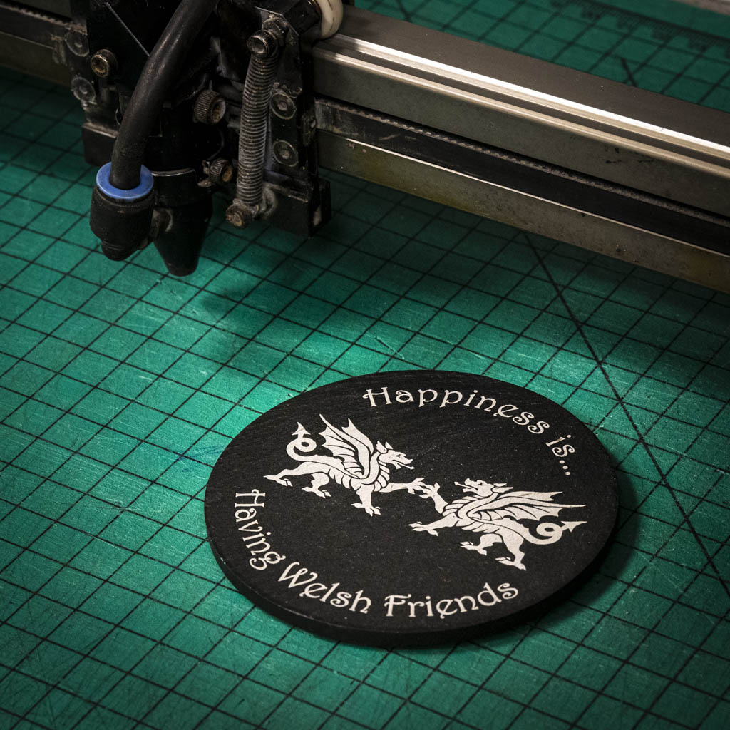 A laser engraved Welsh slate coaster with two welsh dragons and the words happiness is having welsh friends