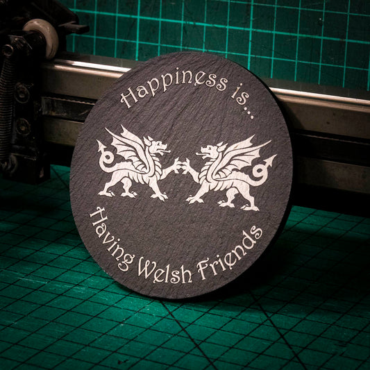 A laser engraved Welsh slate coaster with two welsh dragons and the words happiness is having welsh friends