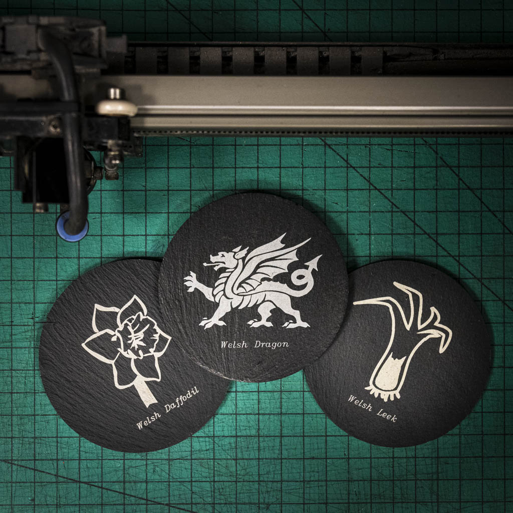 Three laser engraved Welsh slate coaster with the welsh emblems on, a dragon, a leek and a daffodil