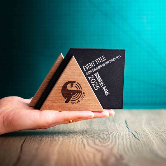An Alpine Award, a laser-engraved, eco-friendly, wooden and slate trophy. The Alpine trophy has two triangular wooden pieces on either side of a square piece of Welsh Slate. The trophy is personalised with Event information and a logo.