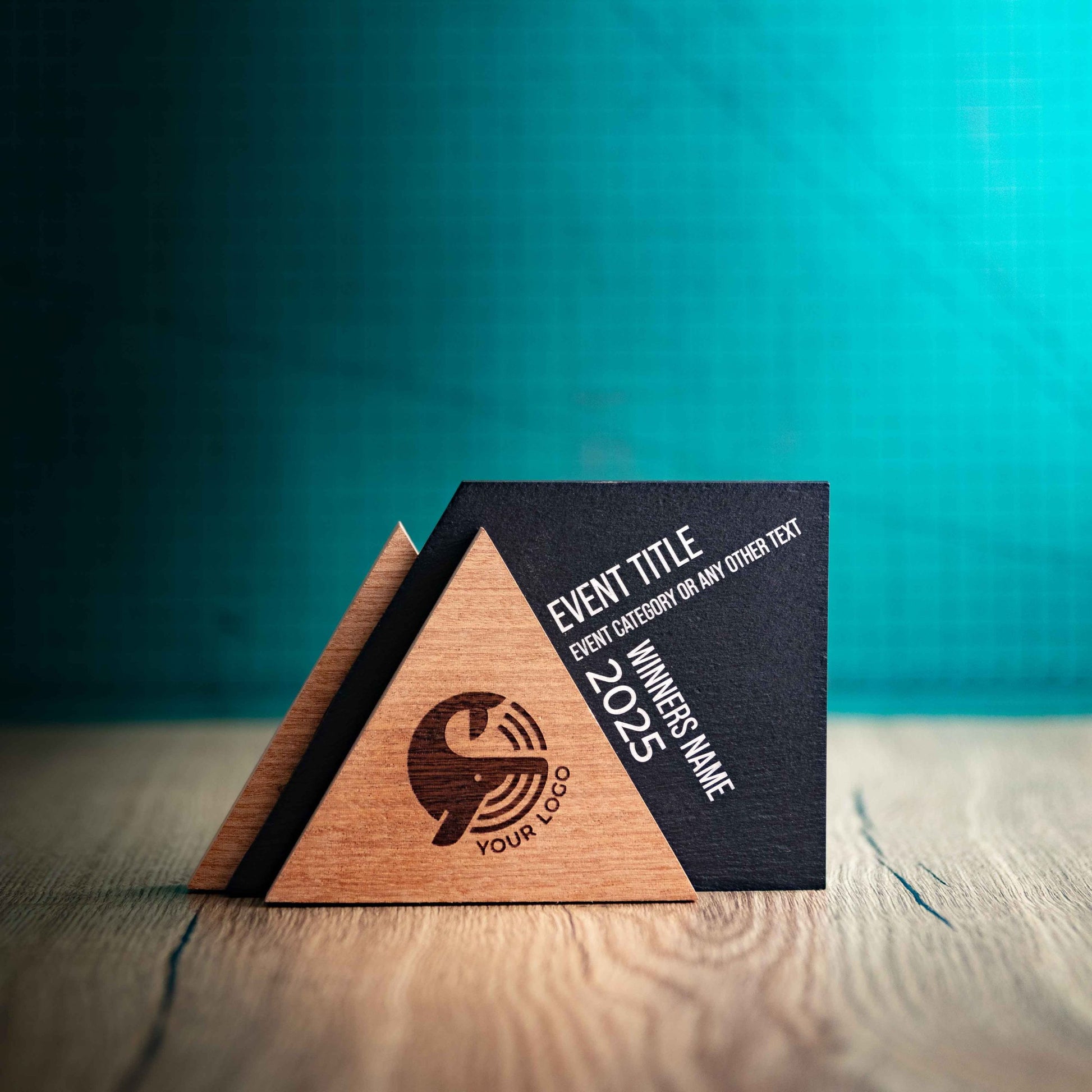 An Alpine Award, a laser-engraved, eco-friendly, wooden and slate trophy. The Alpine trophy has two triangular wooden pieces on either side of a square piece of Welsh Slate. The trophy is personalised with Event information and a logo. 