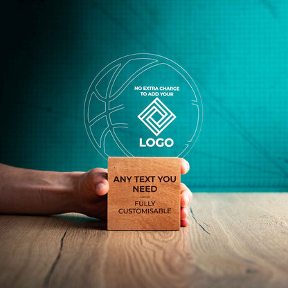A large Basketball trophy with custom text and logos, on an eco-friendly wooden base, with a clear Perspex Basketball mounted on top, featuring fully customisable areas for text and logos, being held to show a size perspective.