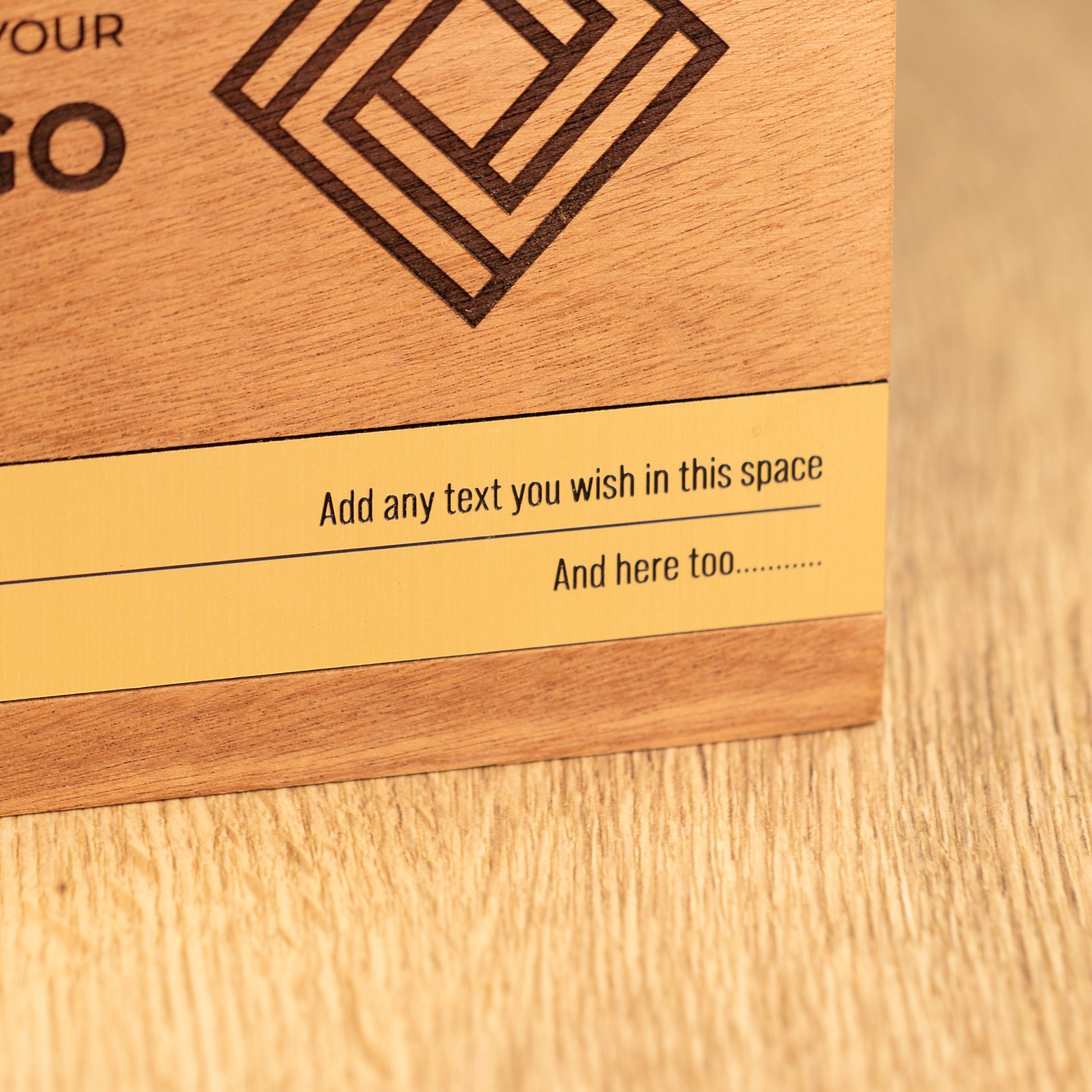 Close-up of the large Bezel wooden trophy showing the gold-coloured metallic inlay set into the lower front, with engraved personalisation text and natural wood grain.