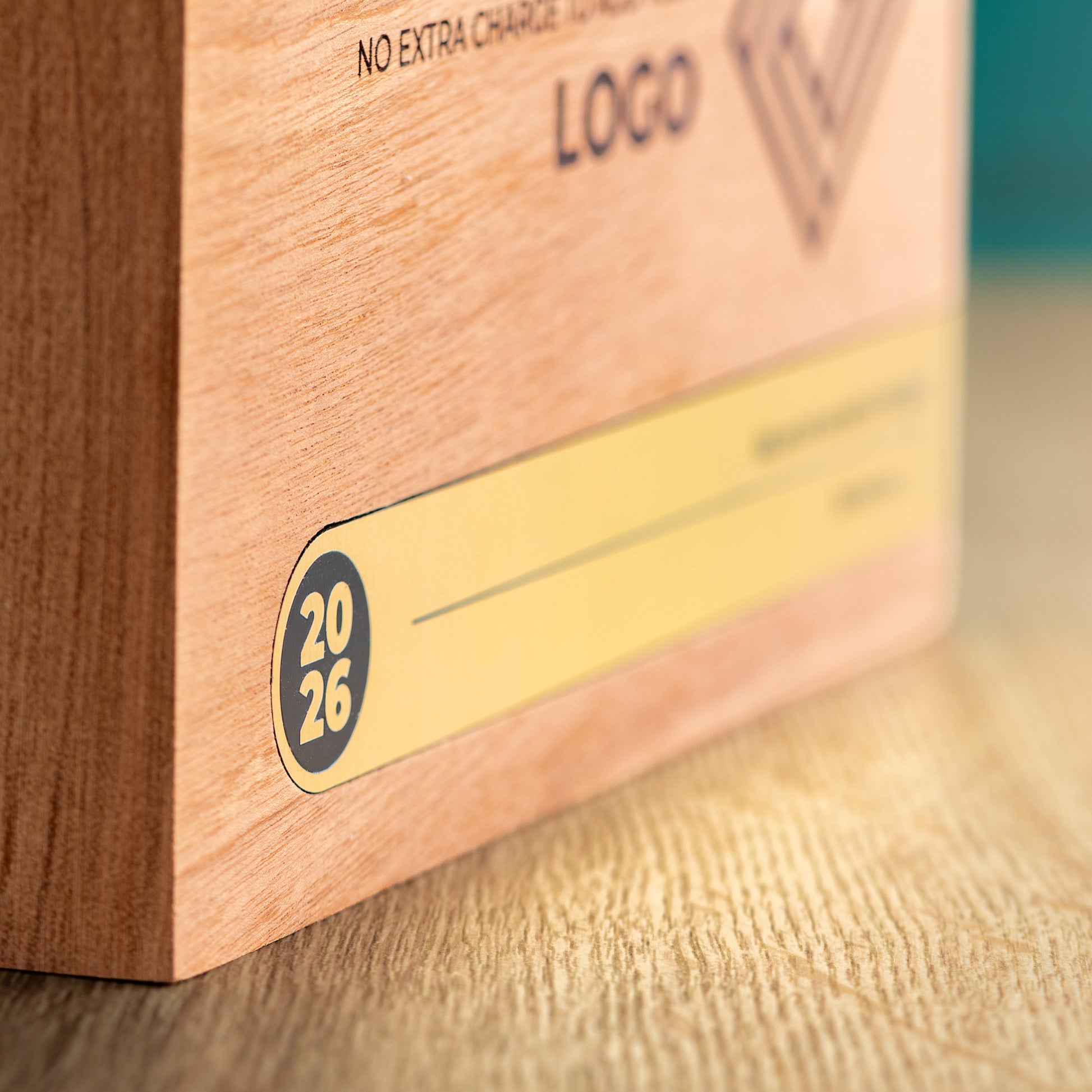 Close-up of the left end of the gold Bezel inlay, showing the rounded 2026 detail and how the metallic section is fitted into the wooden trophy.