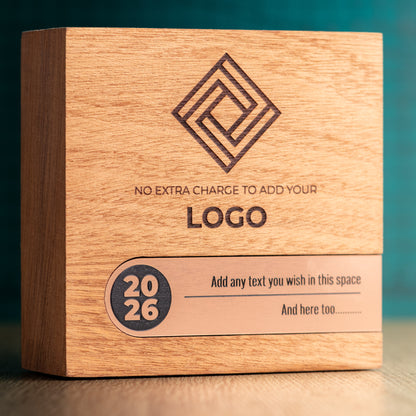 Close front view of a Bezel wooden trophy with an engraved logo above a bronze-coloured metallic inlay, including a circular 2026 detail and space for personalised text.