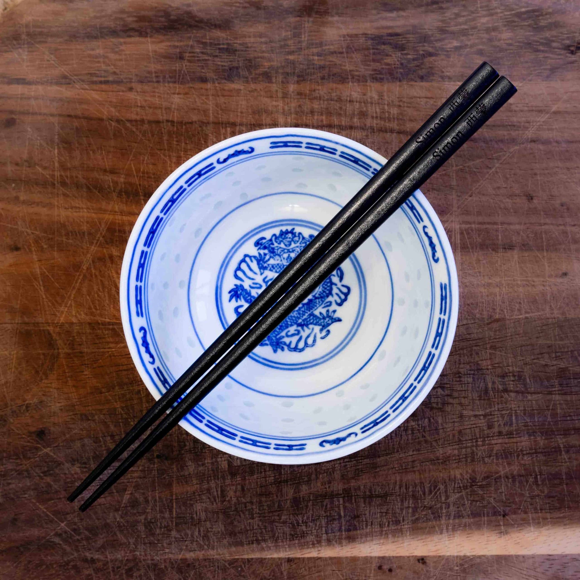 A pair of Japanese-style Chopsticks, colour black wood. The chopsticks are laser engraved and personalised with either a name or a phrase in English and are translated into either Chinese or Japanese.