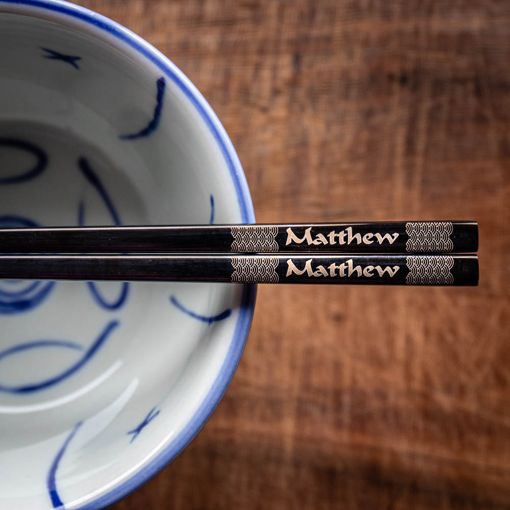 A pair of Chinese-style Metal Coloured Chopsticks - Black. Each pair is personalised with either a name or a phrase.