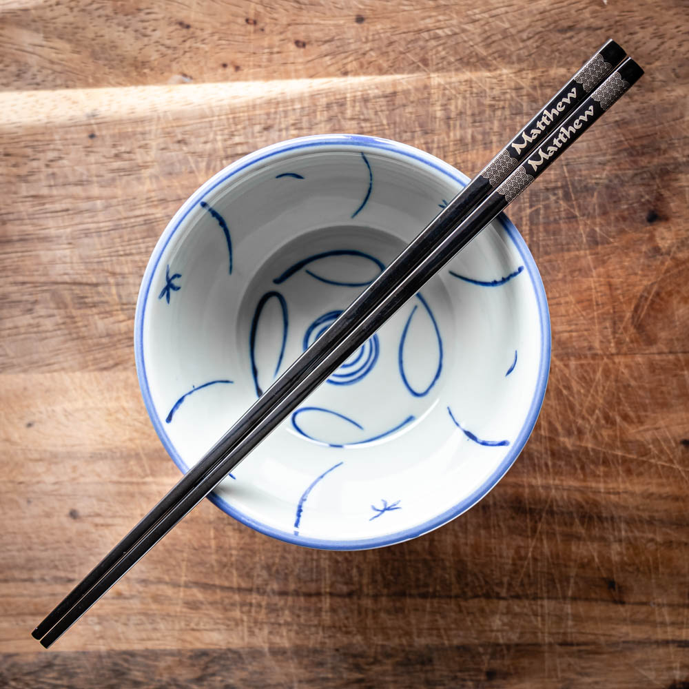 A pair of Chinese-style Metal Coloured Chopsticks - Black. Each pair is personalised with either a name or a phrase.