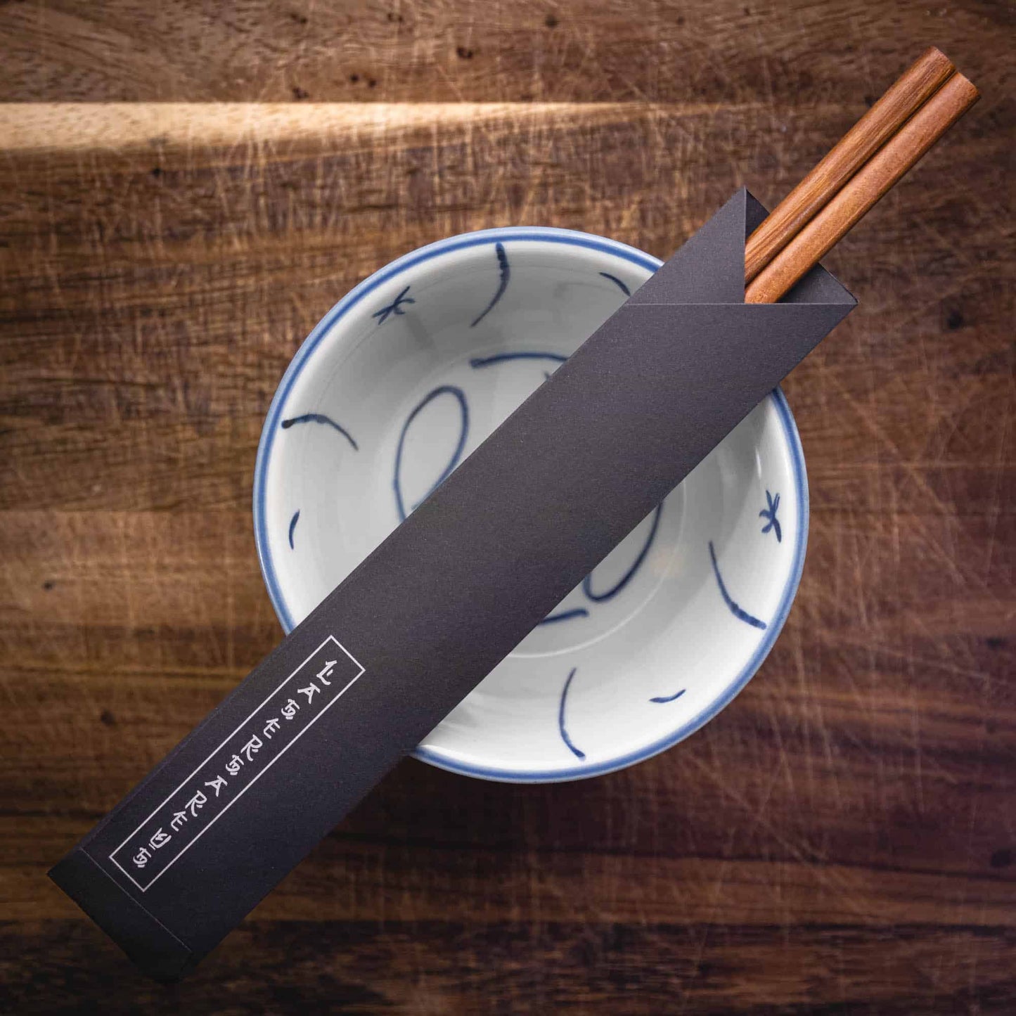 A pair of personalised dark wood Chinese Chopsticks, personalised with a name translated into Chinese in a black paper chopstick pouch