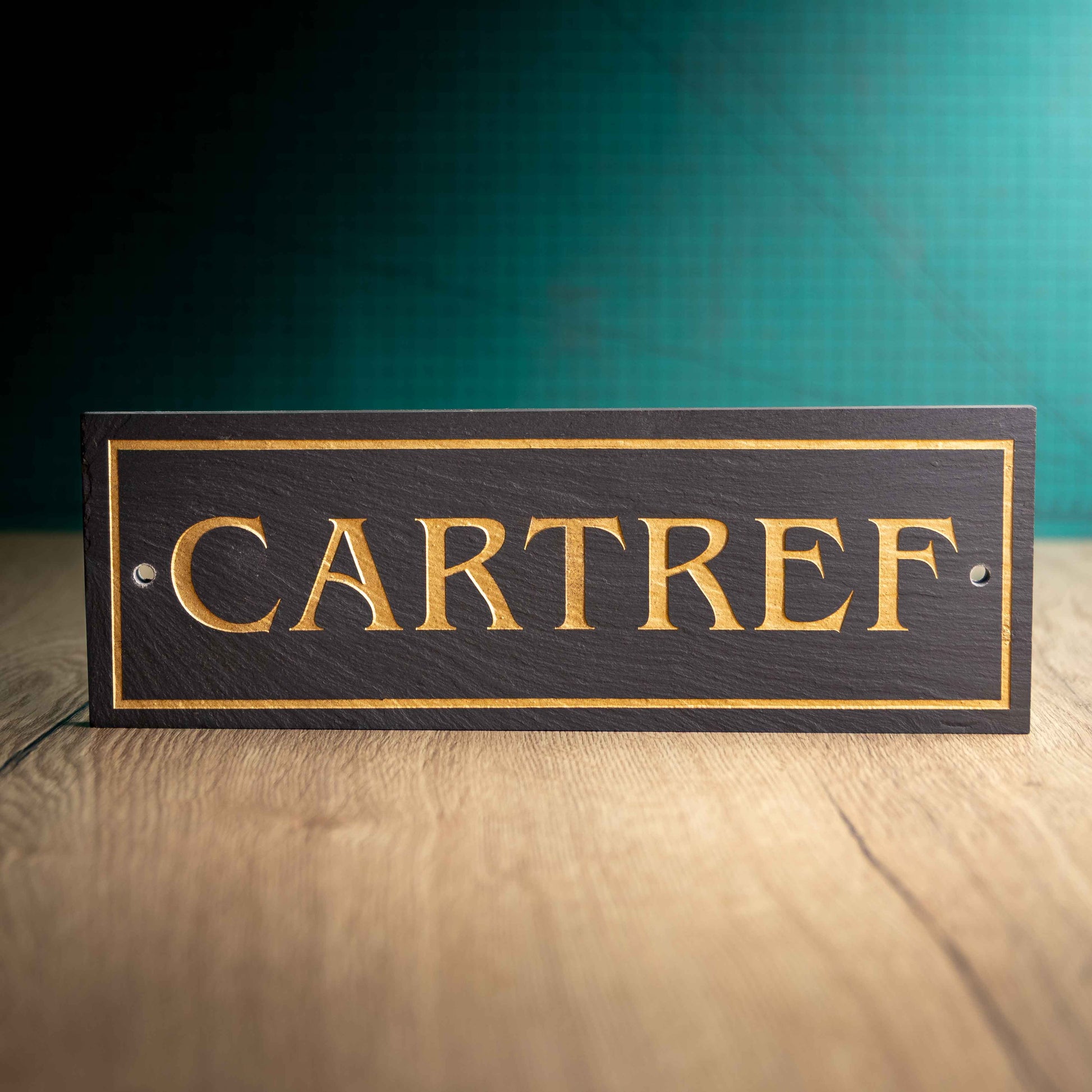A colour-filled slate house sign with 'CARTREF' on a wooden surface and teal background. Long Rectangle 12" x 4" x 0.5"