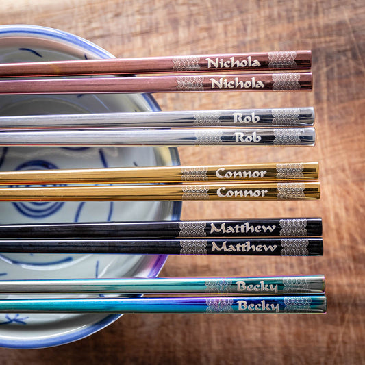 Five pairs of Chinese-style Metal Coloured Chopsticks, Rose Gold, Silver, Gold, Black and Iridescent. Each pair is personalised with either a name or a phrase.