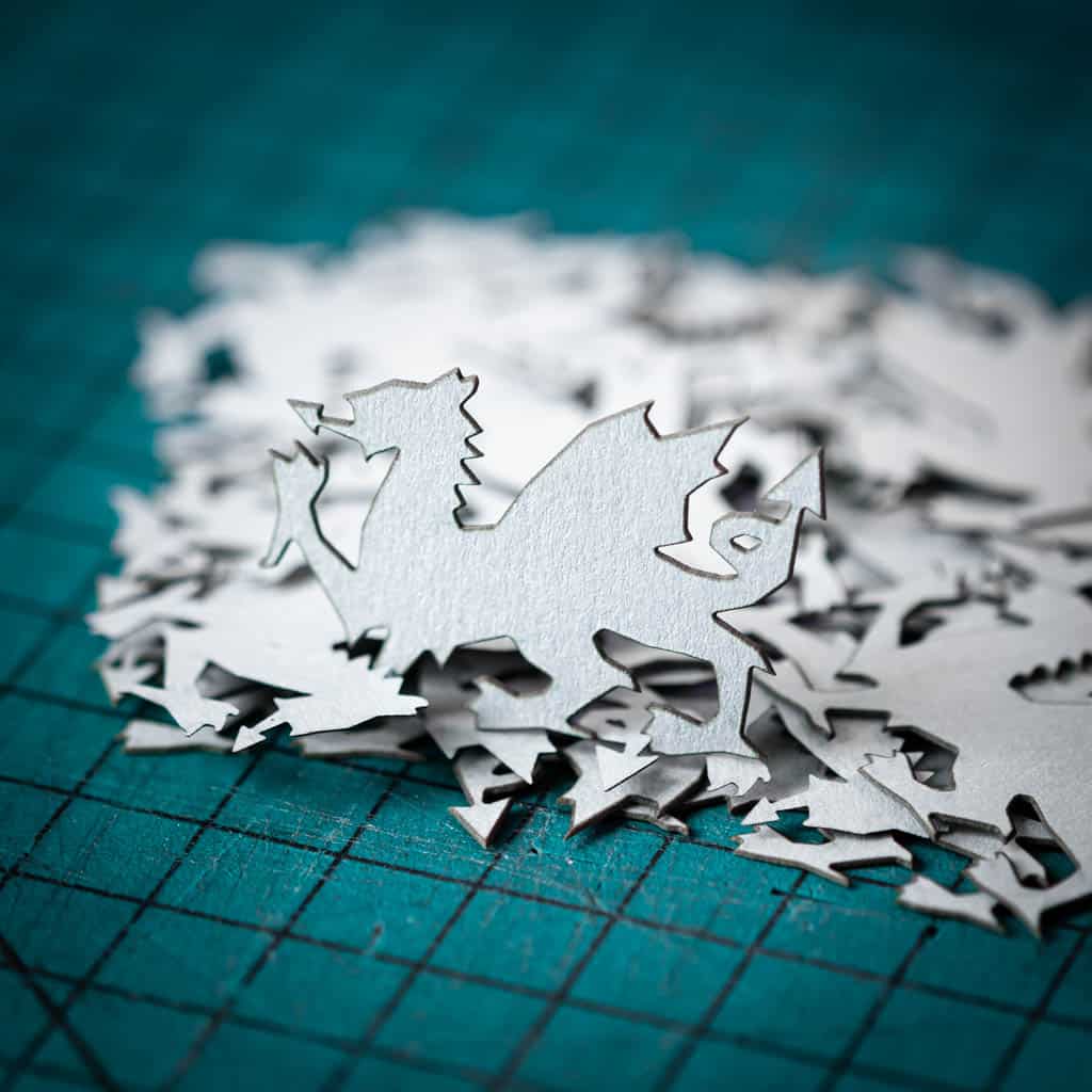A silver dragon confetti laser cut from recycled card