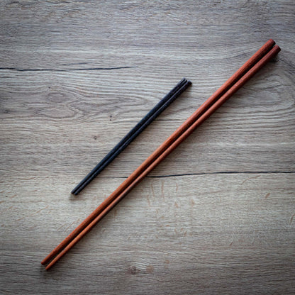 Long wooden cooking chopsticks next to a pair of normal chopsticks for comparison