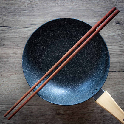Long wooden cooking chopsticks on a wok