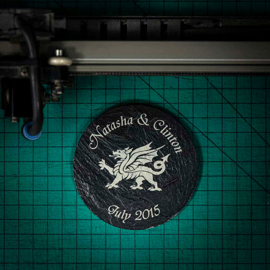 A personalised Welsh slate coaster laser engraved with a welsh dragon, names and a date