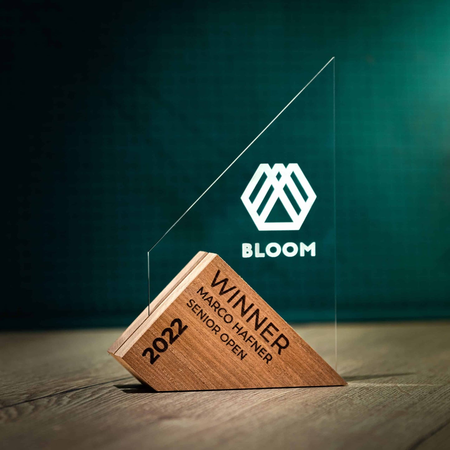 A Large Genoa Award. An Eco-Friendly Wooden and Perspex Award that has a wooden base engraved with a logo and a recyclable clear Perspex triangular shape with a point on the left side of the trophy, which contains the winner and event information.