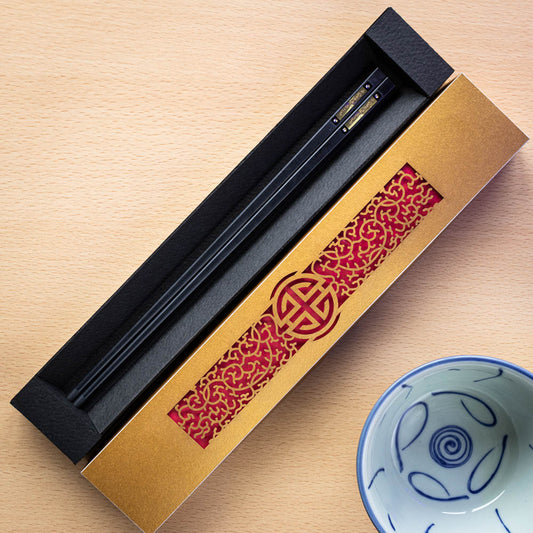 A gold laser cut intricate chopstick presentation box with chopsticks inside