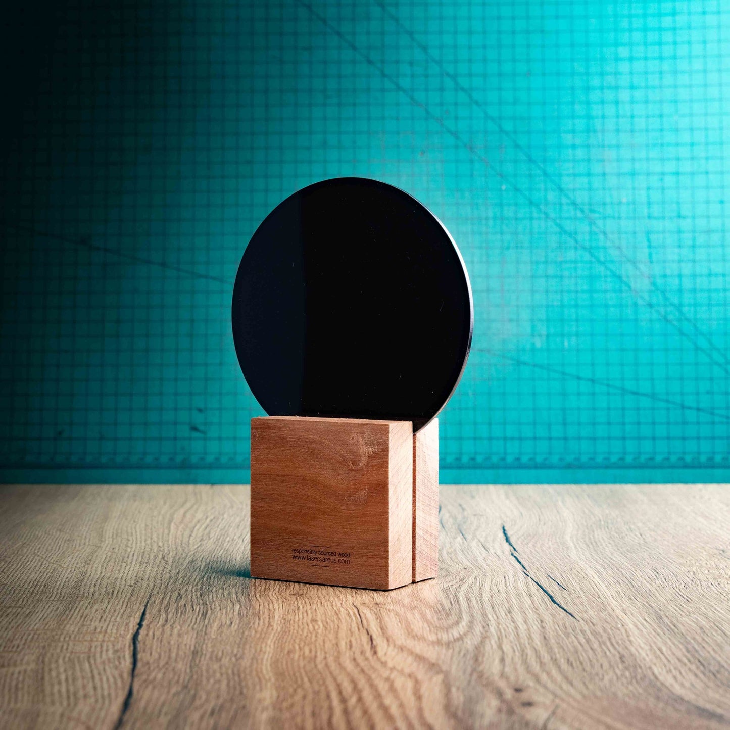 A view of the back of a medium golf award trophy with custom text and logos, on an eco-friendly wooden base, with a black Perspex golf ball mounted on top, with fully customisable areas featuring fully customisable areas for text and logos. A hand is present to show the size of the awards. 