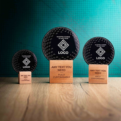 Three golf award trophies with custom text and logos, on eco-friendly wooden bases, with a black Perspex golf ball mounted on top, with fully customisable areas featuring fully customisable areas for text and logos.