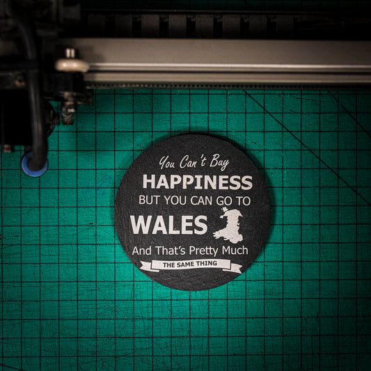 A laser engraved Welsh slate coaster with the words you can't buy happiness but you can go to Wales and that's pretty much the same thing