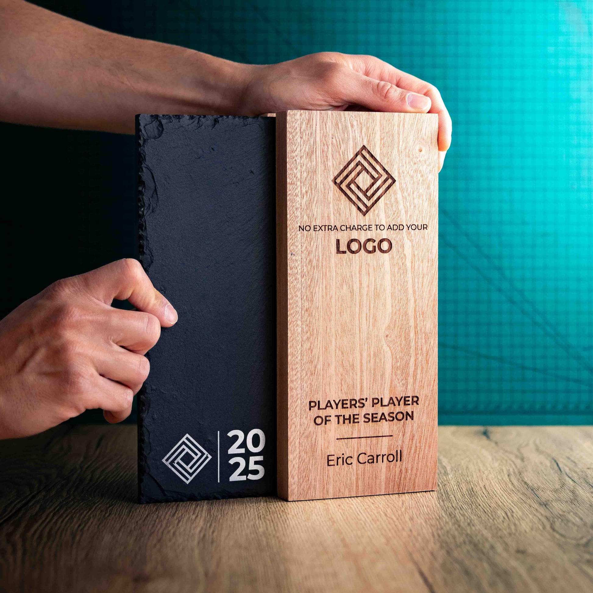 A Large Henge Award, a laser-engraved, eco-friendly wooden and slate trophy, made of two pieces of Sapele wood with a piece of natural Snowdonian slate with a hand holding them to give perspective of size.