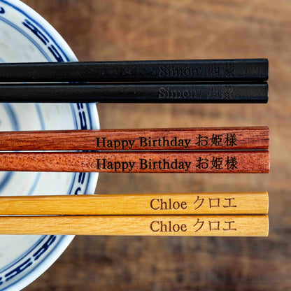 Three pairs of Japanese-style Chopsticks, Black wood, Rose wood and Light wood. Each pair is personalised with either a name or a phrase in English and is translated into either Chinese or Japanese.