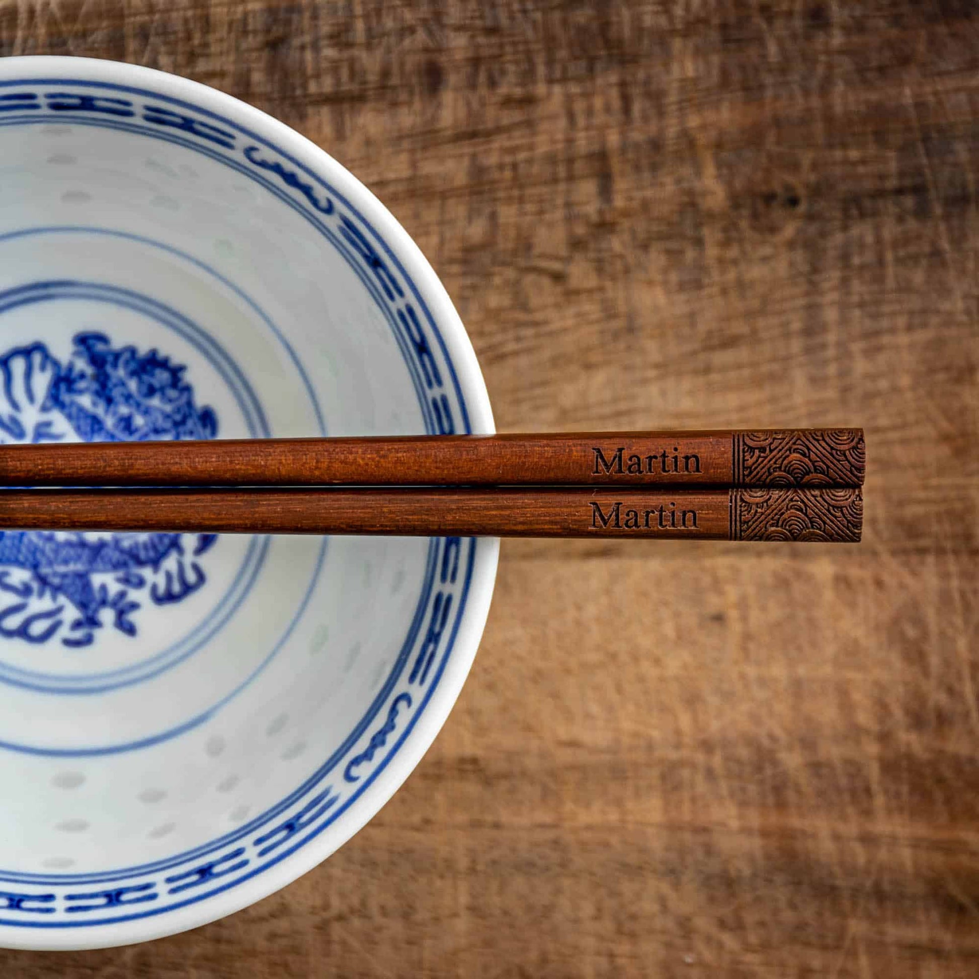 A pair of Japanese-style Chopsticks, Dark wood. The pair is personalised with either a name or a phrase in English, translated into either Chinese or Japanese, and features a contemporary design at the end of the chopsticks.