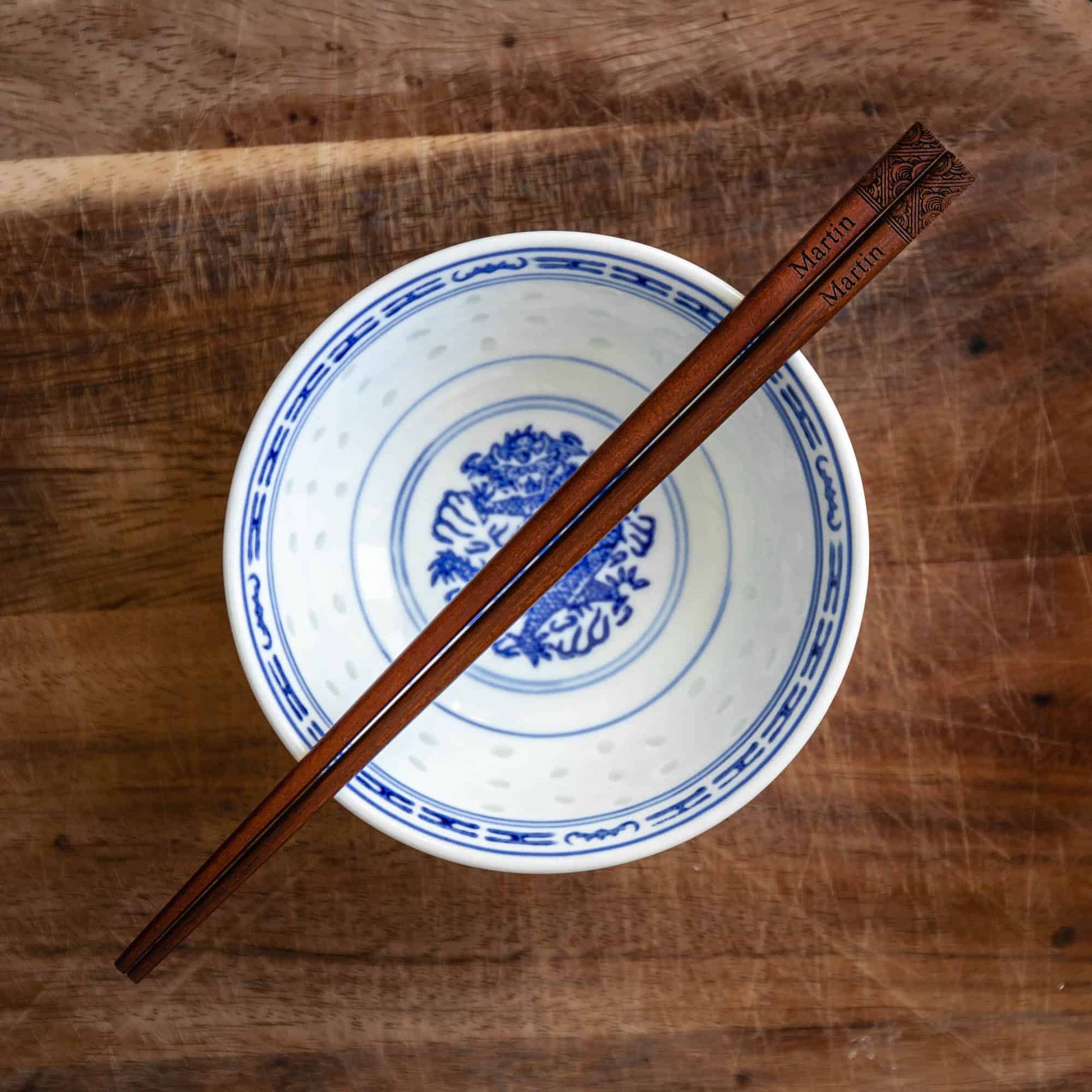 A pair of Japanese-style Chopsticks, Dark wood. The pair is personalised with either a name or a phrase in English, translated into either Chinese or Japanese, and features a contemporary design at the end of the chopsticks.