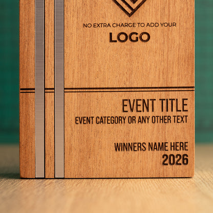 Front close-up of a Kingdom trophy showing two parallel silver metallic inlays flush with the wood on the left, alongside engraved event title, category, winner name and year text.