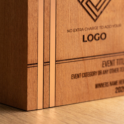 Angled close-up of the left side of a Kingdom wooden trophy, showing two bronze-toned metallic inlays running vertically through the front face and sitting flush with the surrounding wood.