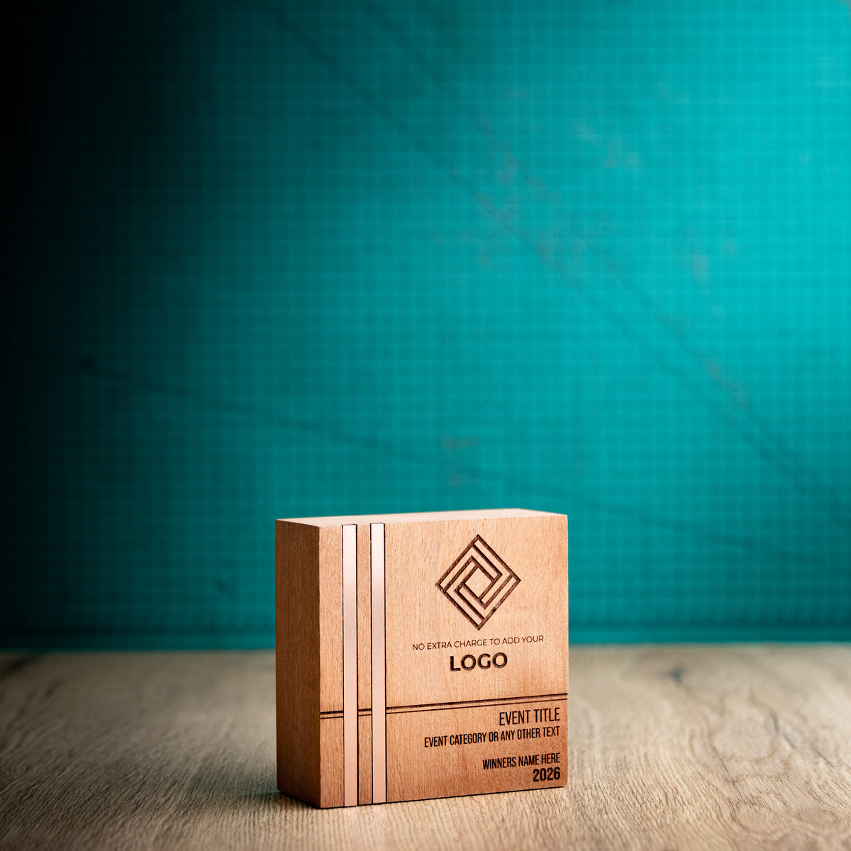 Three-quarter view of the small square Kingdom wooden trophy, showing its thick block construction and two bronze-toned metallic inlays running the full height near the left edge of the front face.