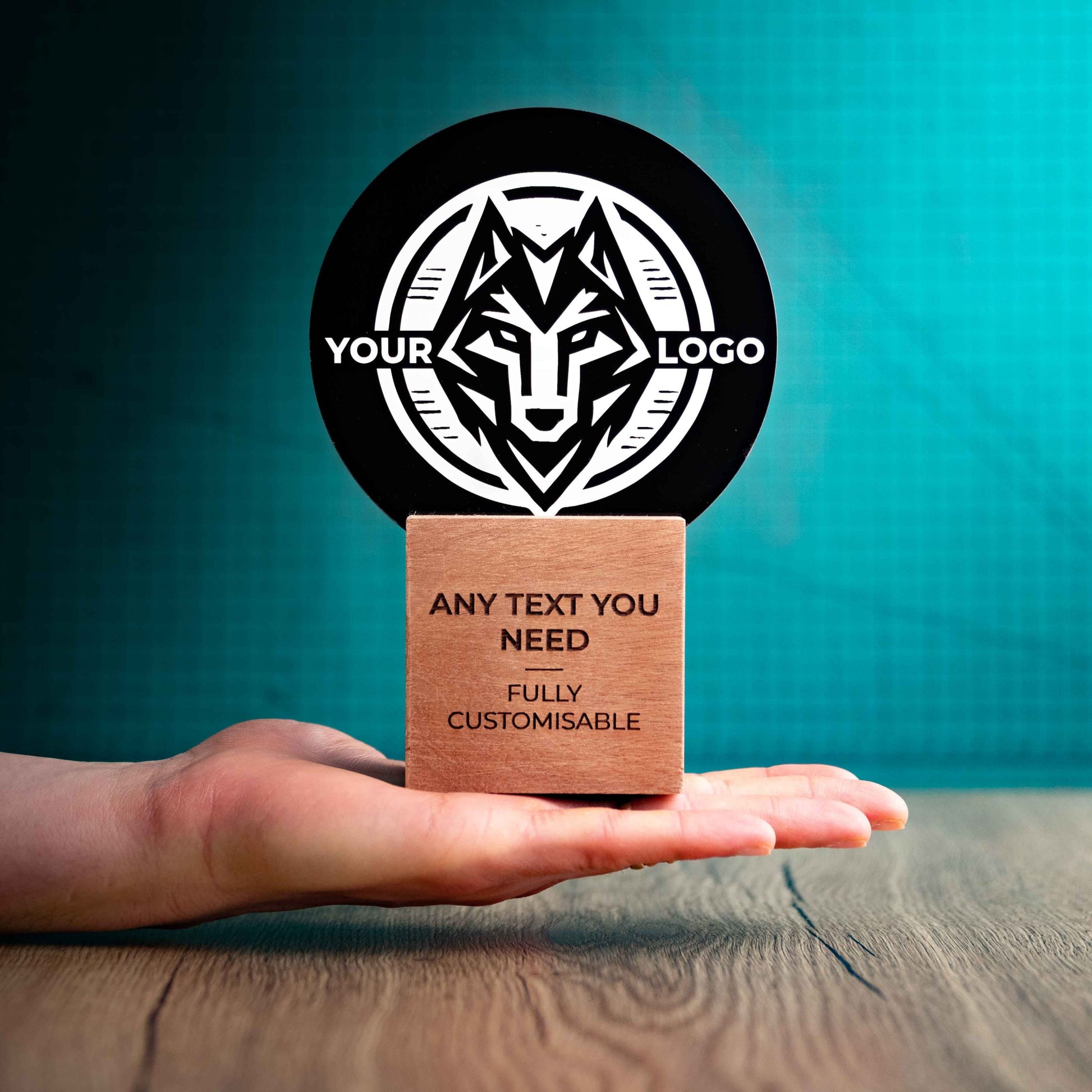 A medium Legacy trophy with custom text and logos, on an eco-friendly wooden base, with a black Perspex circle mounted on top, featuring fully customisable areas for text and logos, being held to show a size perspective.