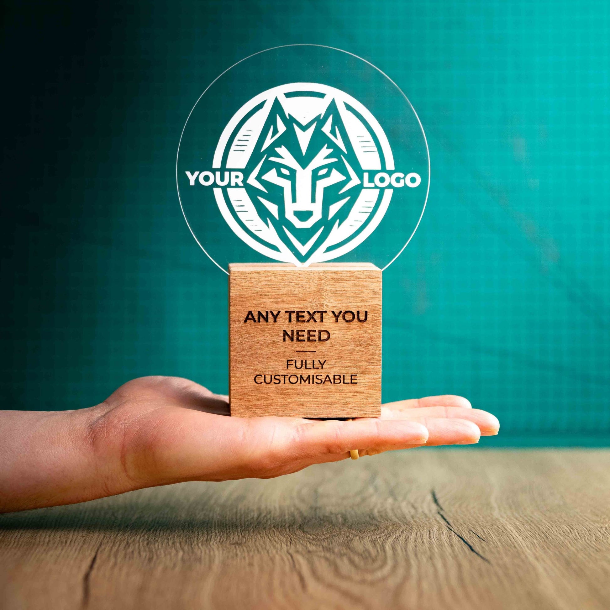 A medium Legacy trophy with custom text and logos, on an eco-friendly wooden base, with a clear Perspex circle mounted on top, featuring fully customisable areas for text and logos, being held to give a size perspective.